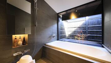 A modern bathroom with a large bathtub, a glass-enclosed shower, and a built-in shelf with toiletries.