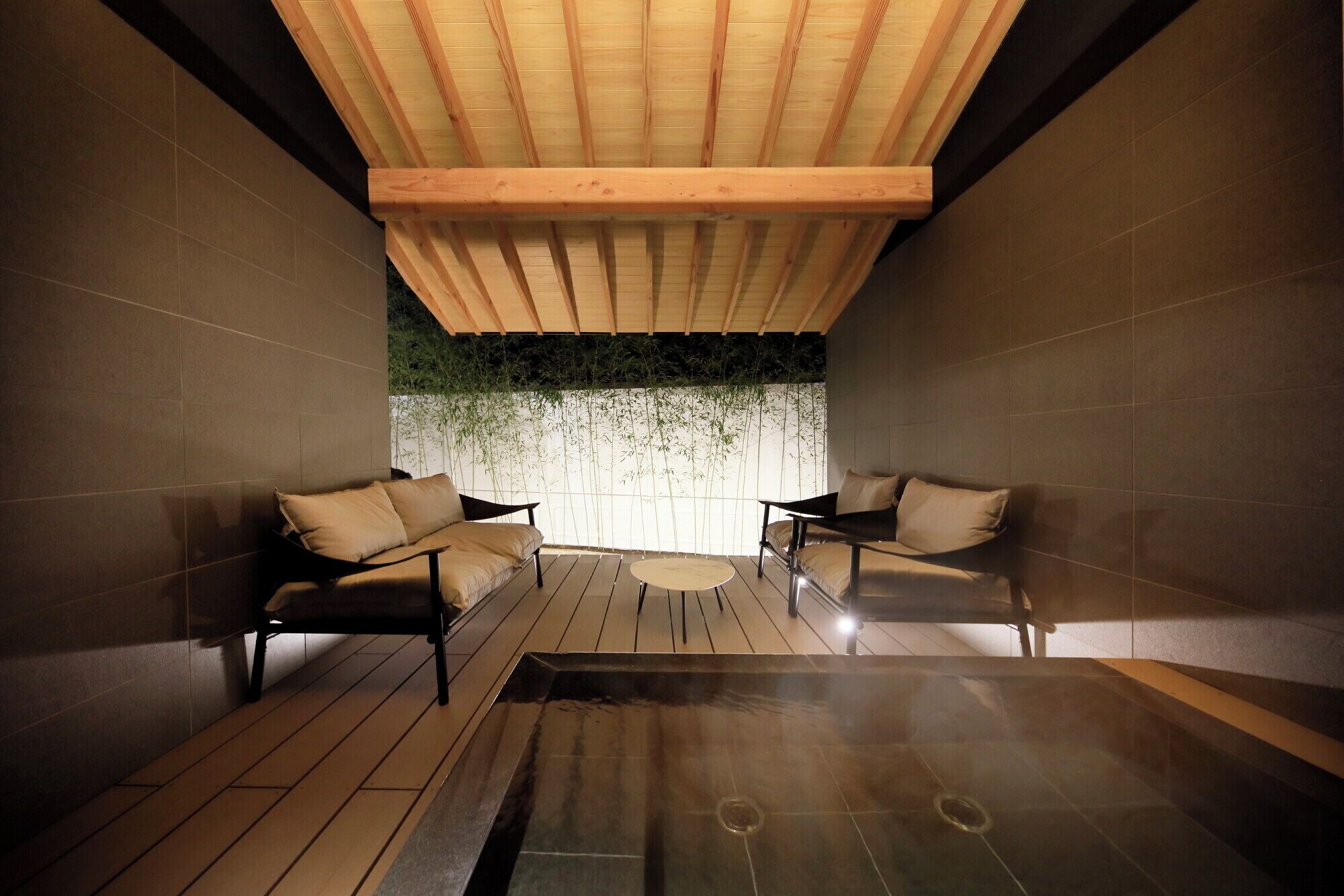 A spa room with two sofas, a small round table, and a hot tub.