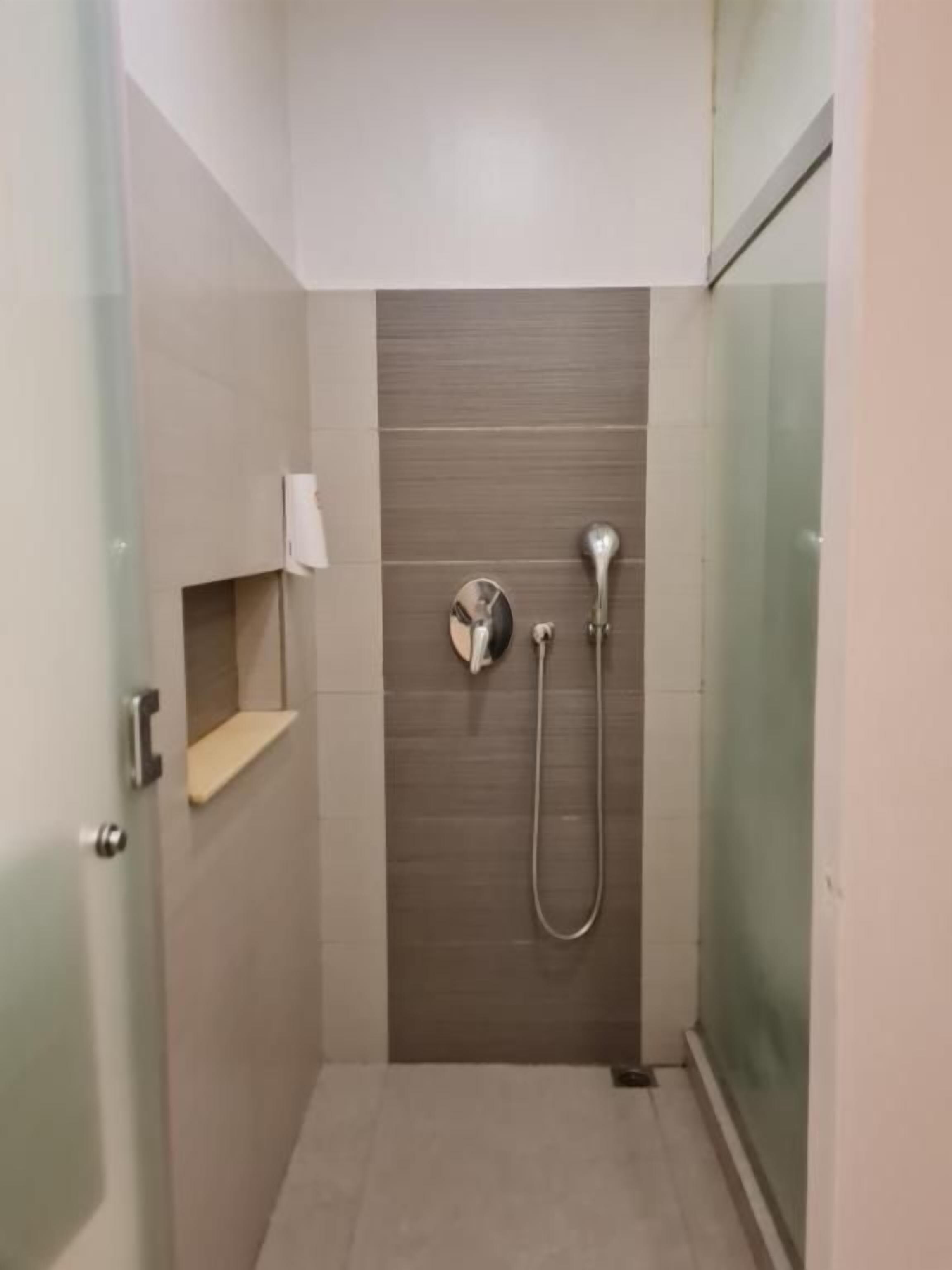 Une salle de bain moderne dotée d’une douche à parois de verre, d’un pommeau de douche à main et d’un robinet mural.
