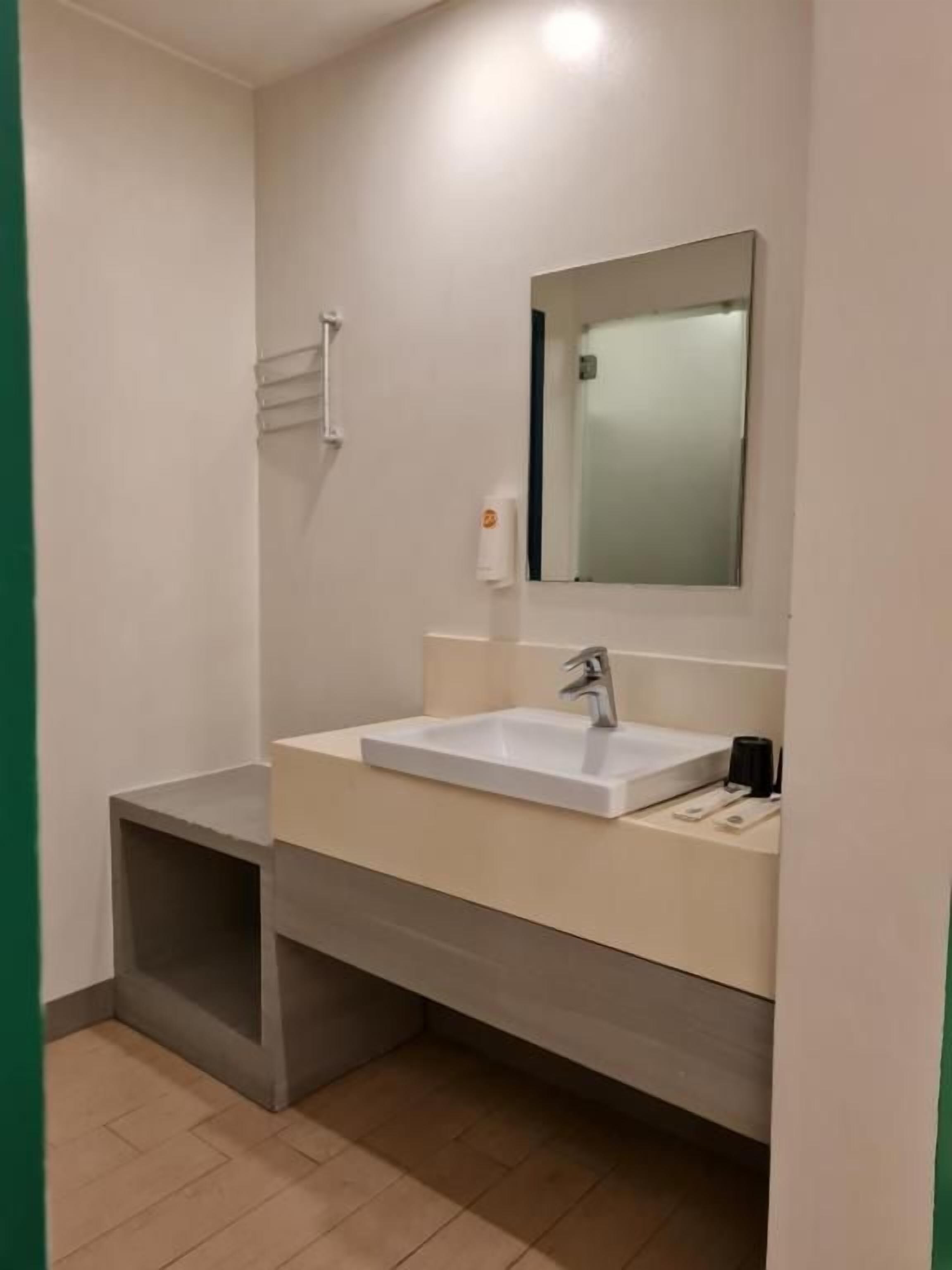 Une salle de bain avec un lavabo blanc, un miroir et un porte-serviettes.