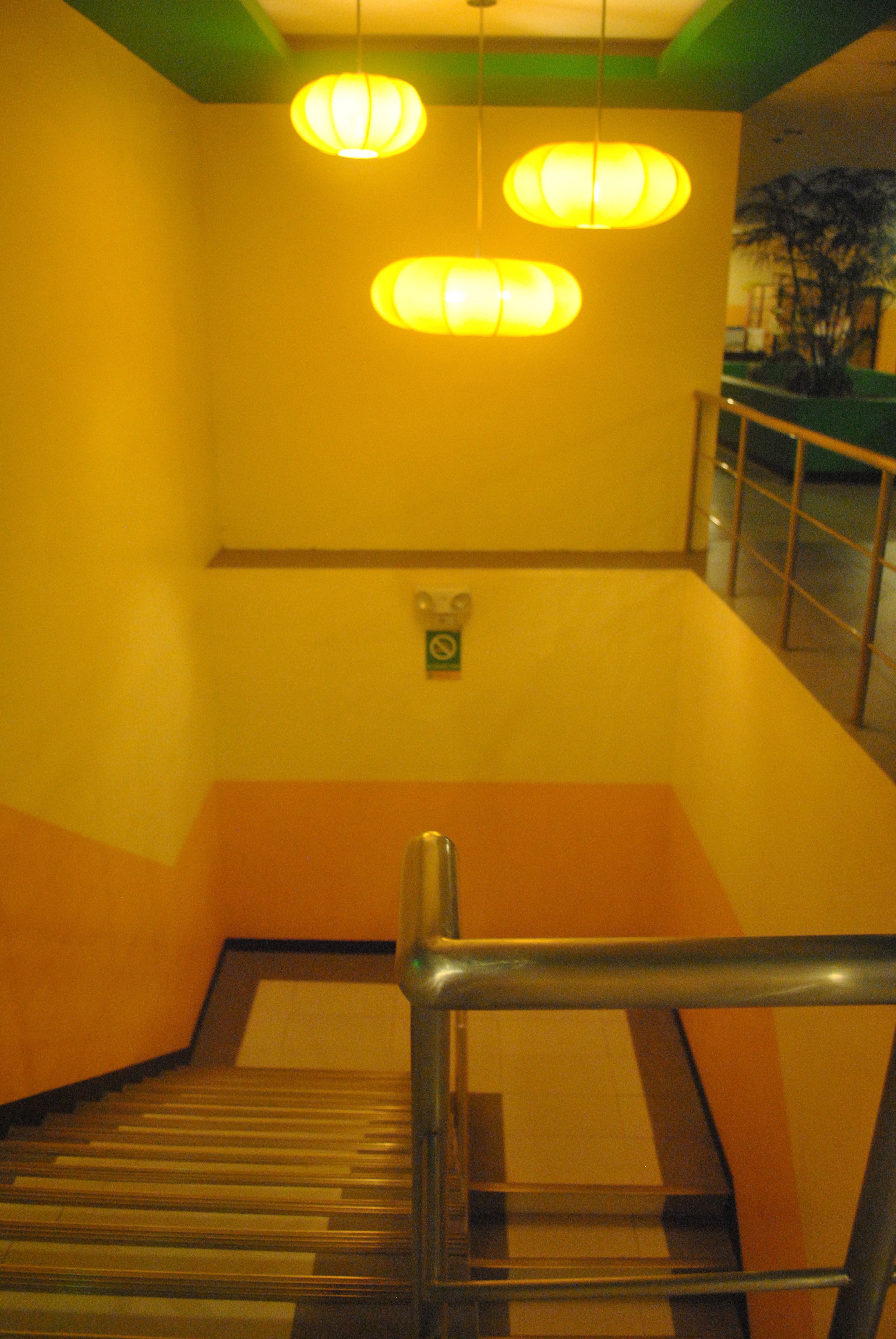 A staircase with a metal handrail, a yellow wall, and a green floor.