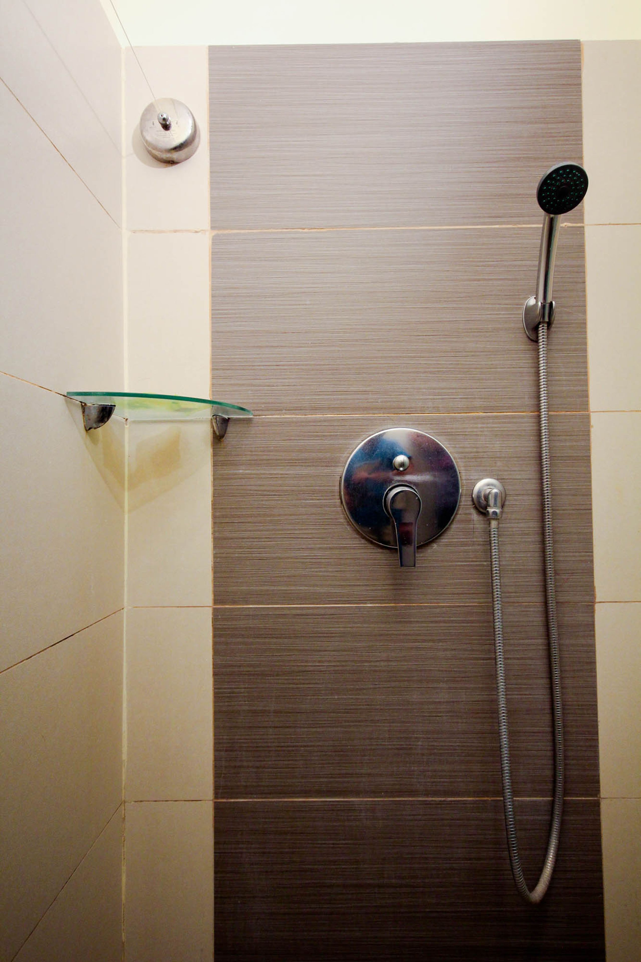 A shower with a handheld showerhead and a wall-mounted faucet.