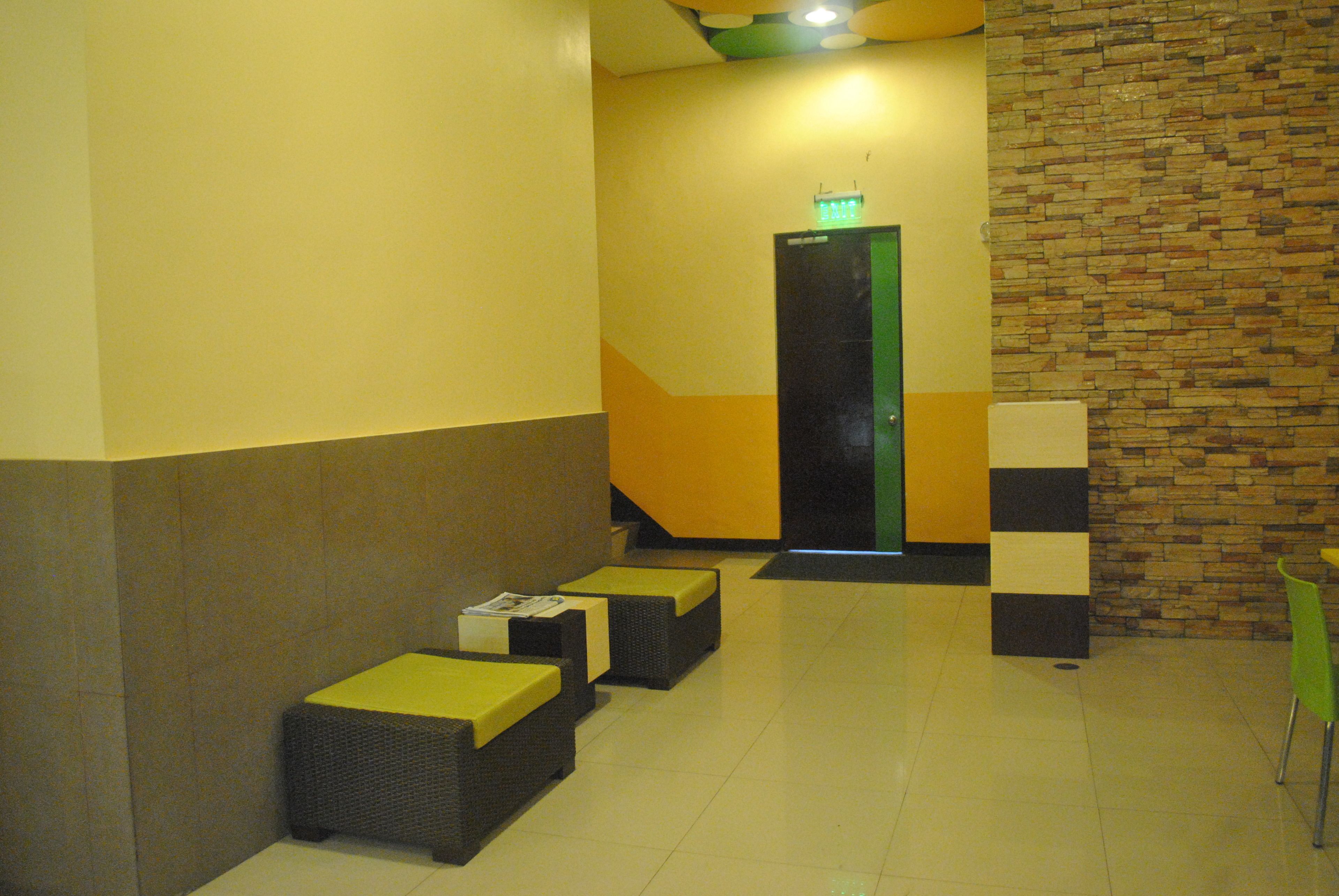 A lobby with a modern design, featuring a staircase, a reception area, and seating with cushions.
