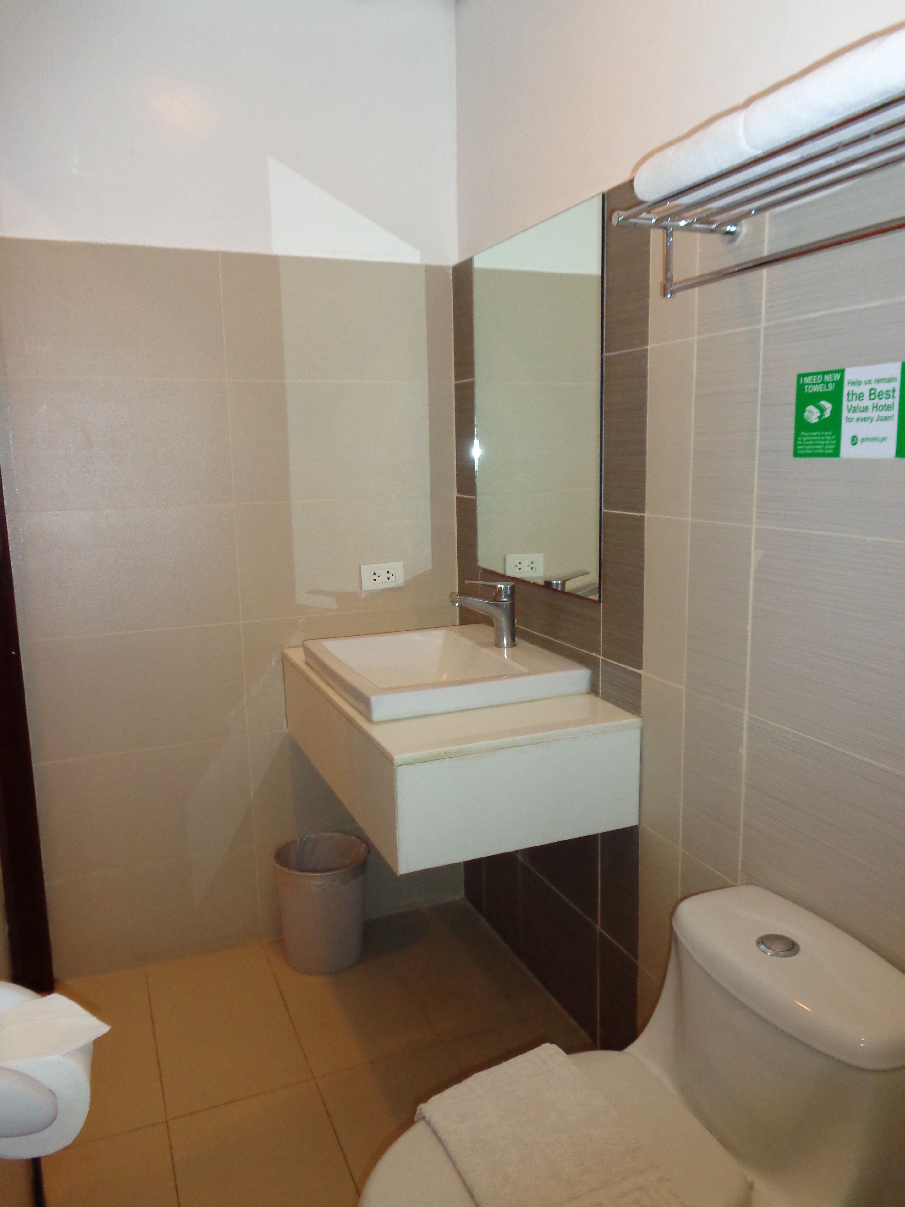 Un bagno piccolo con lavandino, specchio e water. Si vede un cestino e un portasciugamani.