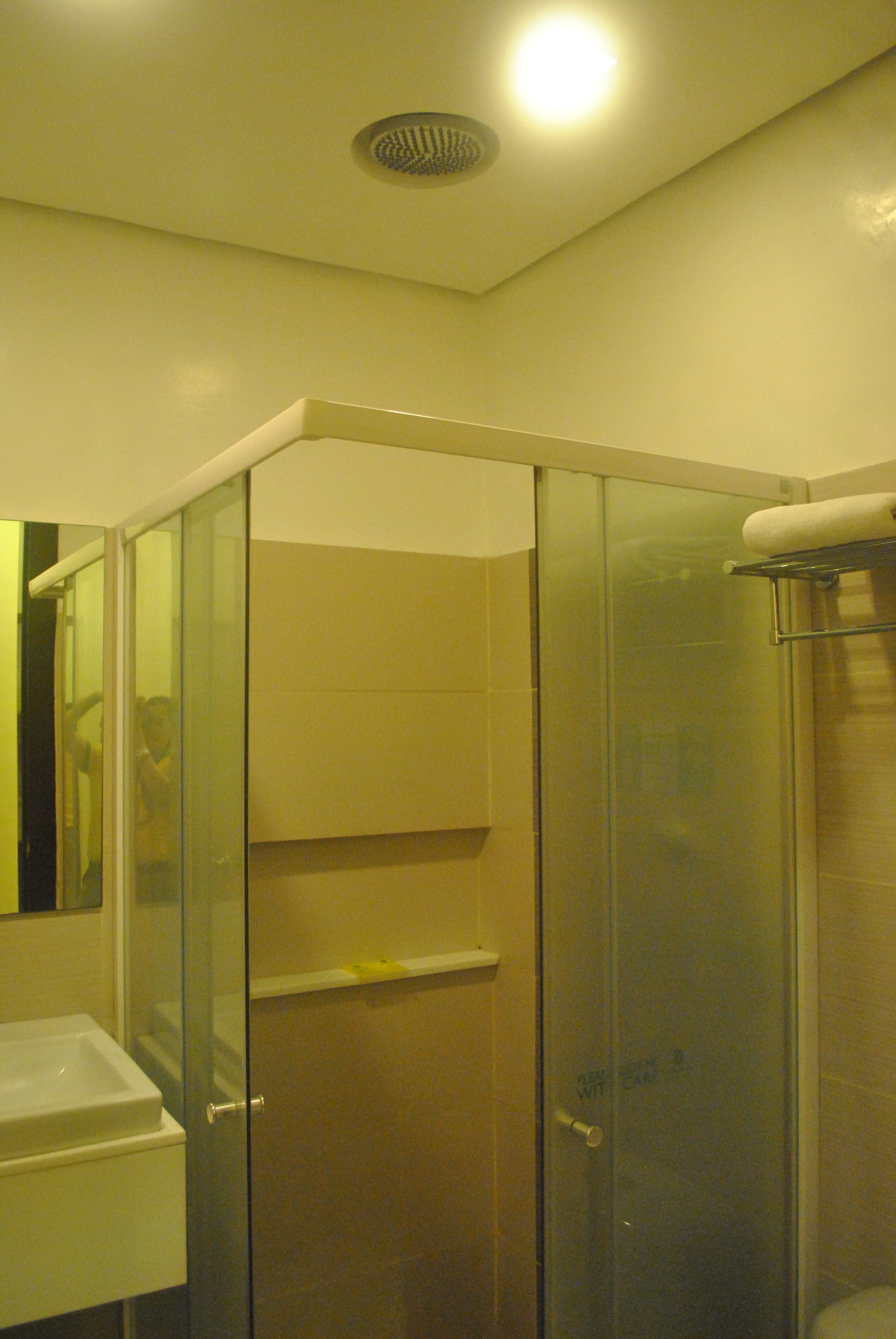 A glass-enclosed shower stall with a white sink and a towel rack.