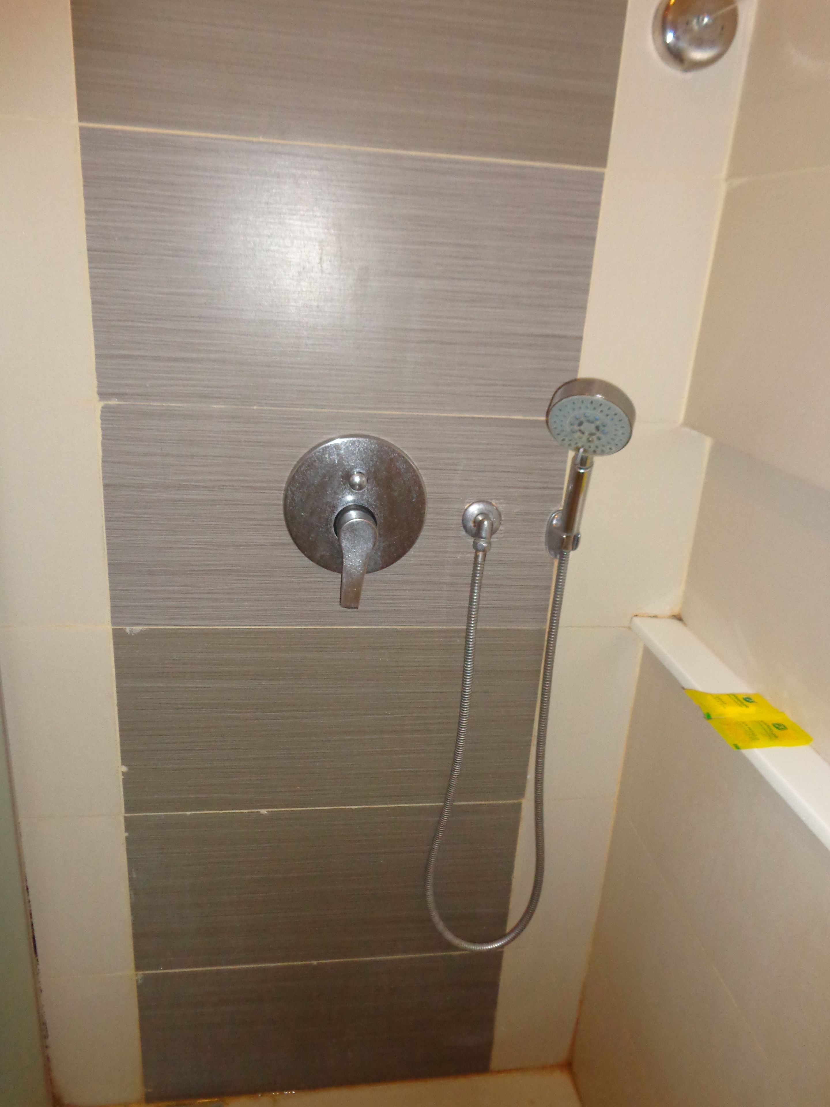 A shower with a handheld showerhead and a wall-mounted faucet.