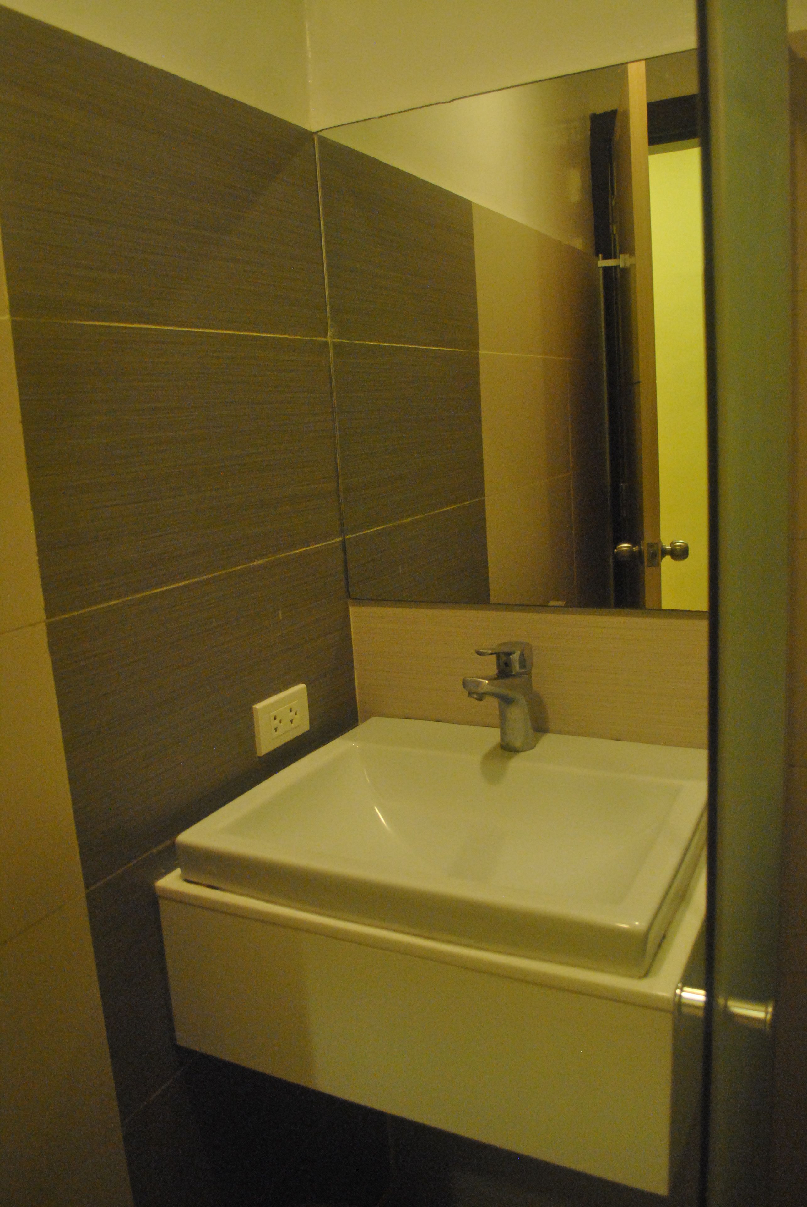 A bathroom with a white sink, a mirror, and a door.