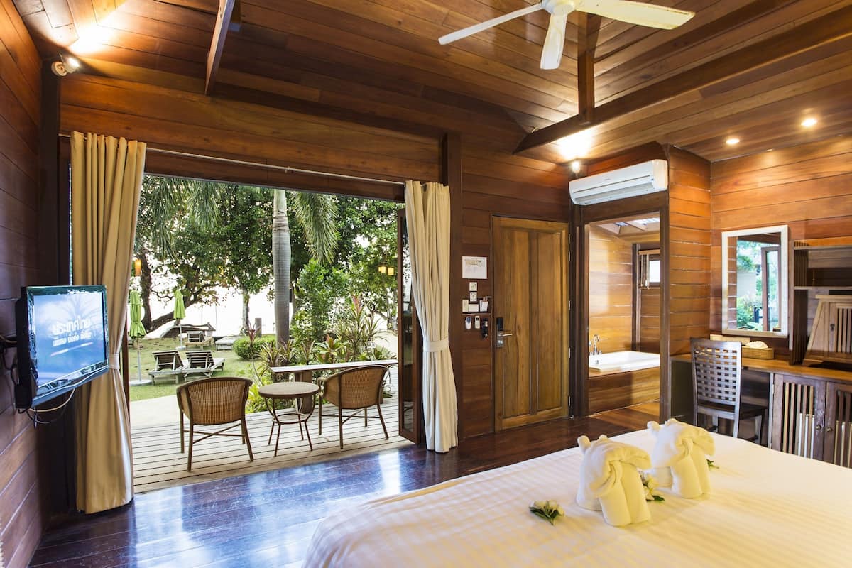A hotel room with a bed, a television, a bathroom, and a view of the outdoors.