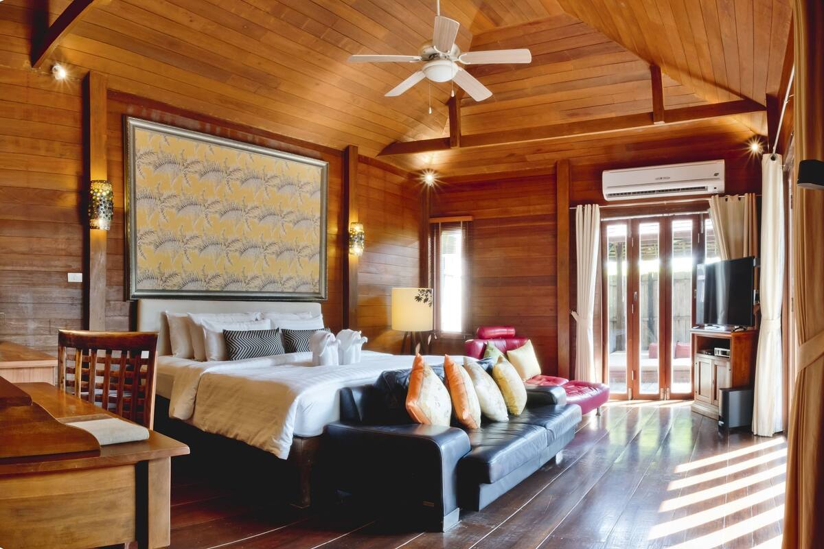 A wooden cabin-style room with a bed, sofa, and a TV.