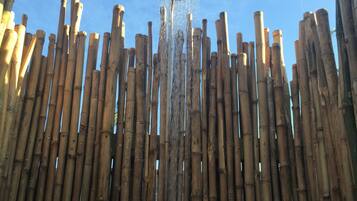 Une clôture en bambou agrémentée d’un élément décoratif aquatique au centre.