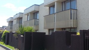 Une rangée d’immeubles d’appartements modernes à deux étages, dotés de balcons et de grandes fenêtres.