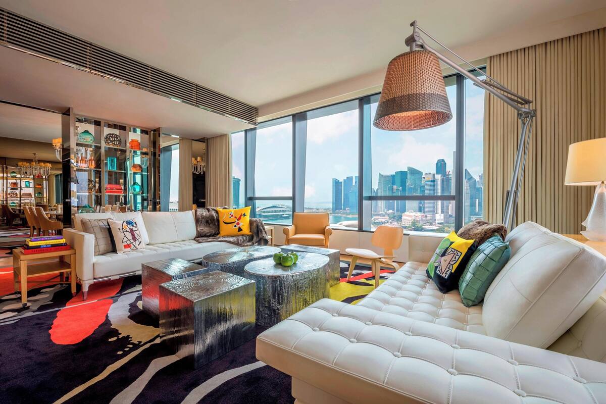 A modern living room with a white sofa, a coffee table, and a city view through large windows.