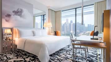 A hotel room with a large bed, a desk, and a view of the city skyline.