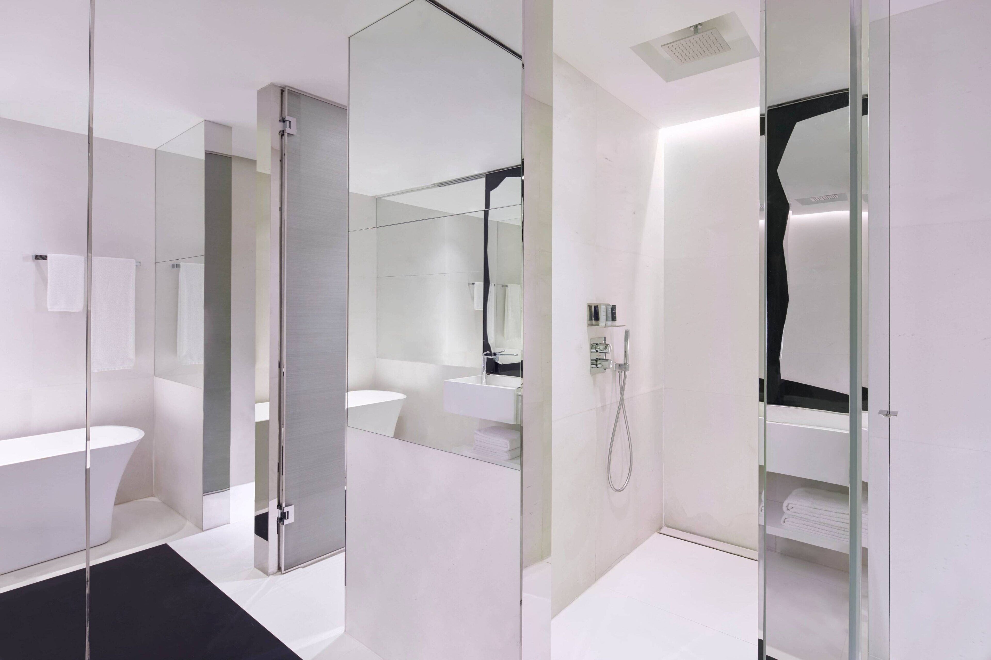 A modern bathroom with a glass shower enclosure, a white sink, and a large mirror.