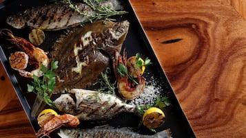 A tray of grilled fish with lemon slices and herbs.