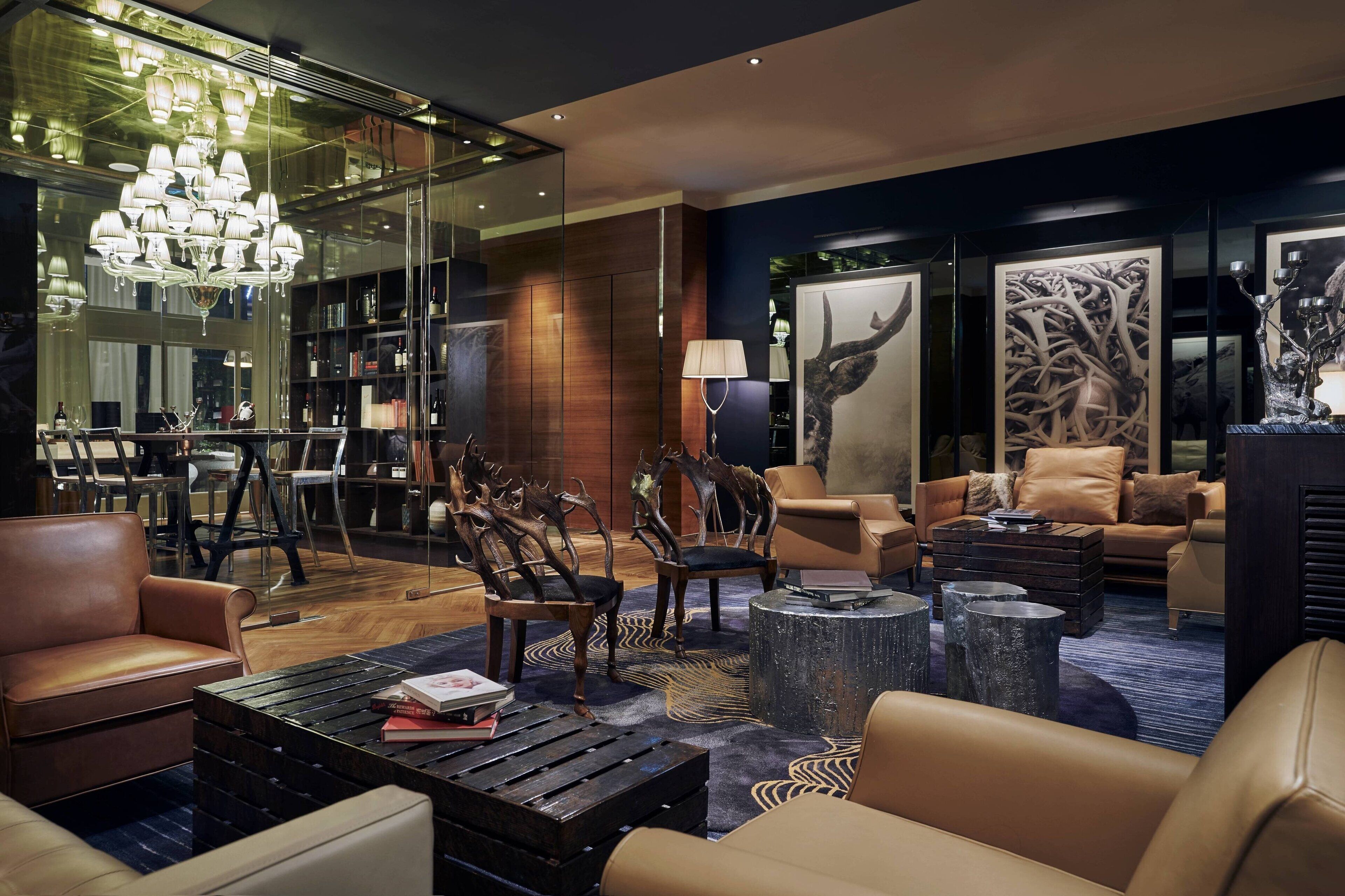 A modern lounge area with leather sofas, a coffee table, and a chandelier.