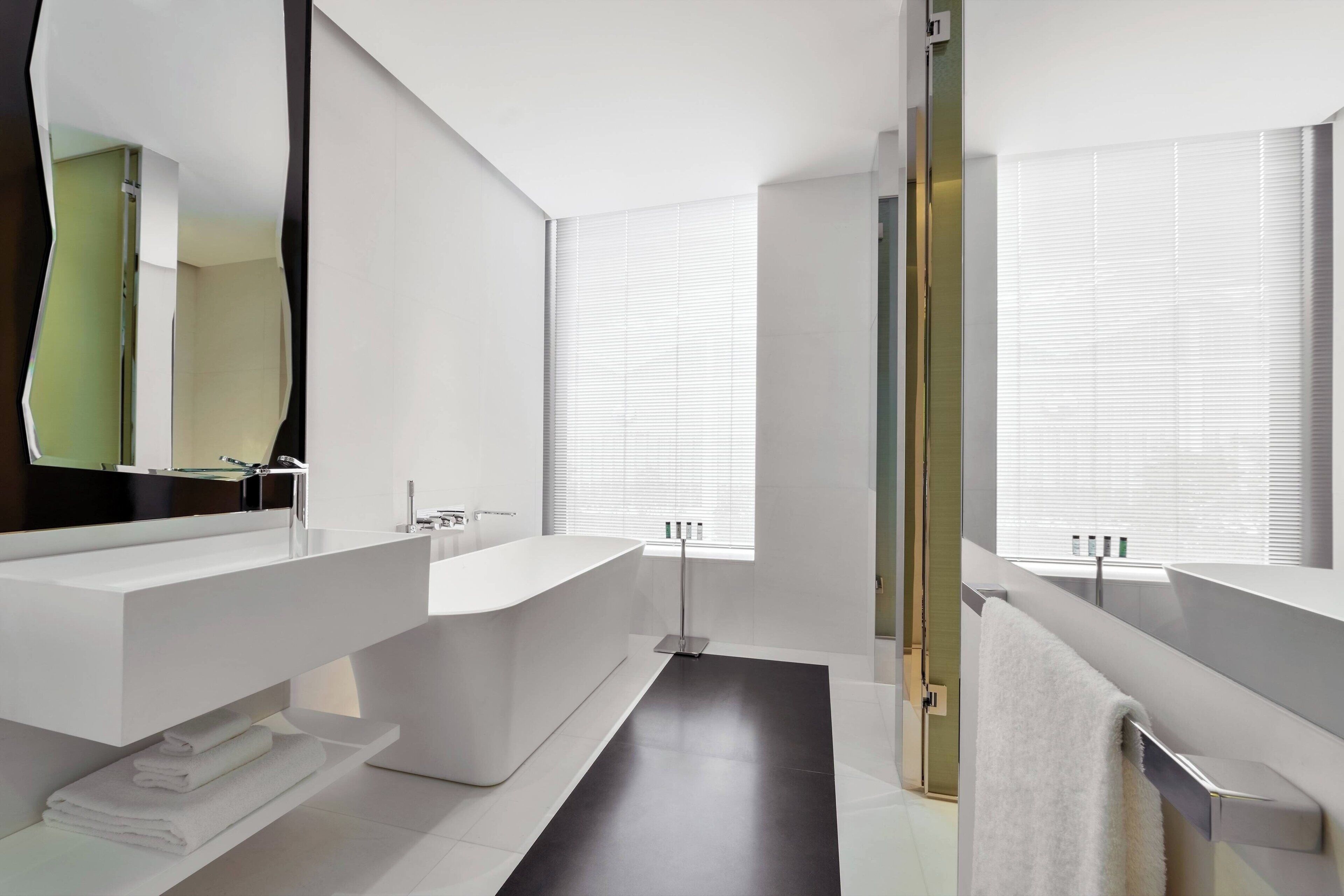 Un baño moderno con una bañera blanca grande, un tocador con espejo y un perchero para toallas.