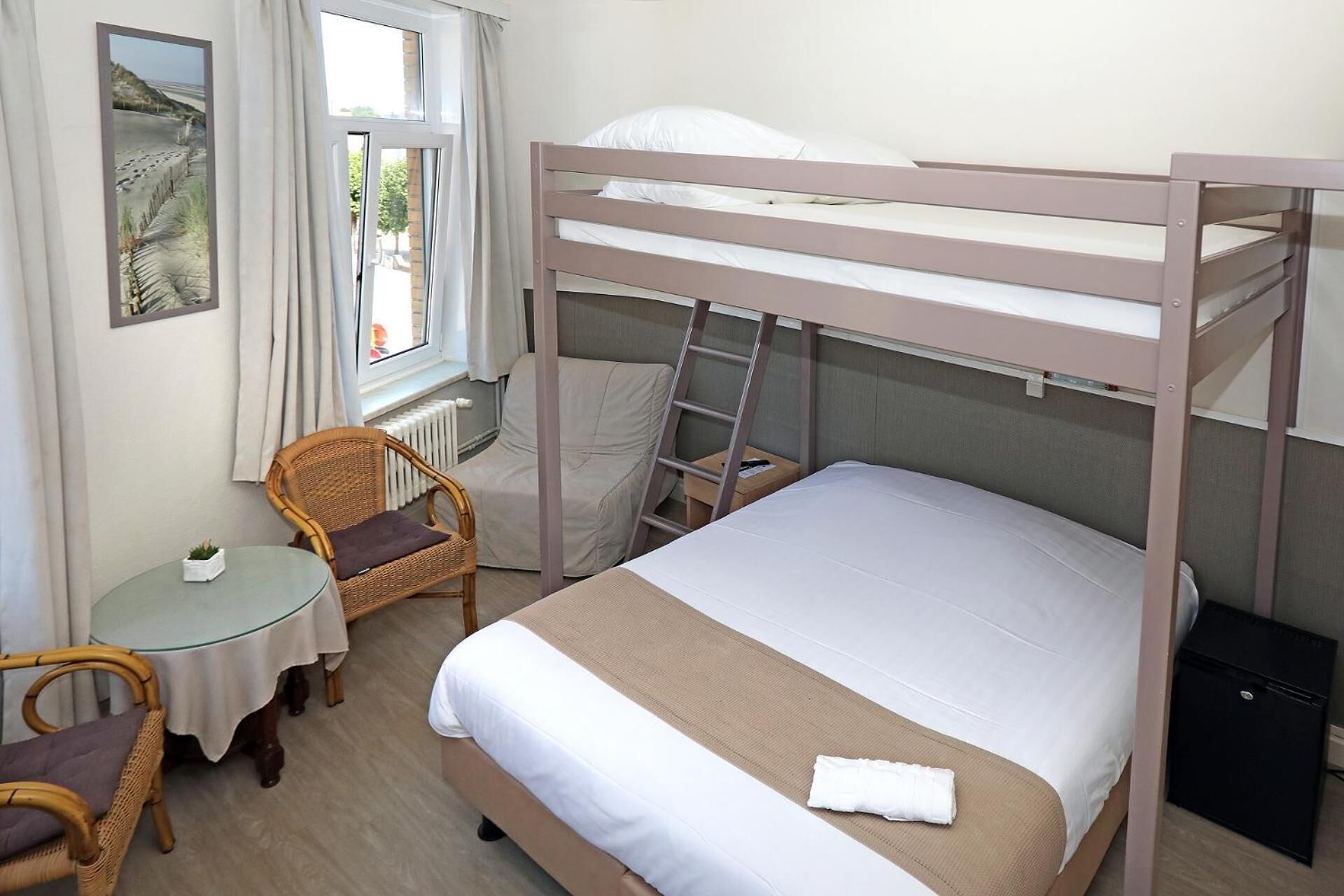 A bunk bed room with a small table, chair, and a window with a view of the beach.