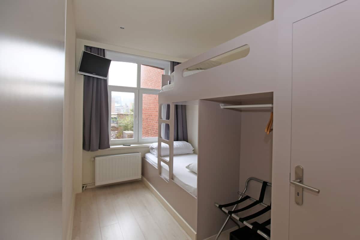 Une chambre avec un lit superposé, une fenêtre avec des rideaux, un radiateur et une porte.