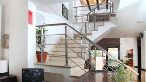 Un interior moderno con una escalera, un mostrador de recepción y un sistema de cámaras de seguridad.