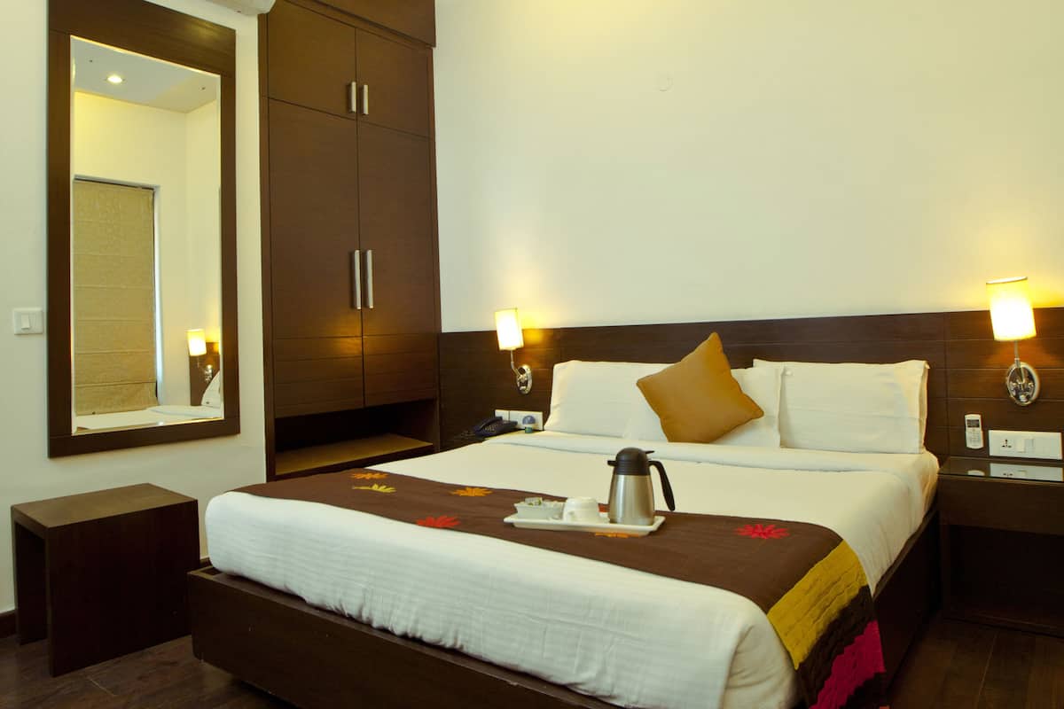 Una habitación de hotel con una cama grande, una mesita de noche, un espejo y un aire acondicionado instalado en la pared.