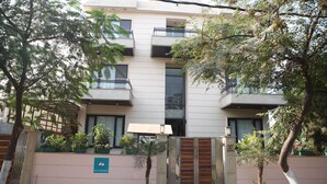 Un edificio de varios pisos con balcones, una entrada con reja y plantas en macetas.