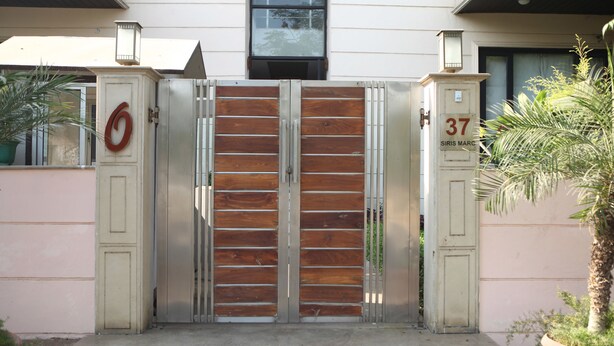 Una entrada con puerta de rejas y doble puerta, un letrero con el número '6' y otro con el '37' y la inscripción 'SIRIS MARC' en la fachada de un edificio.