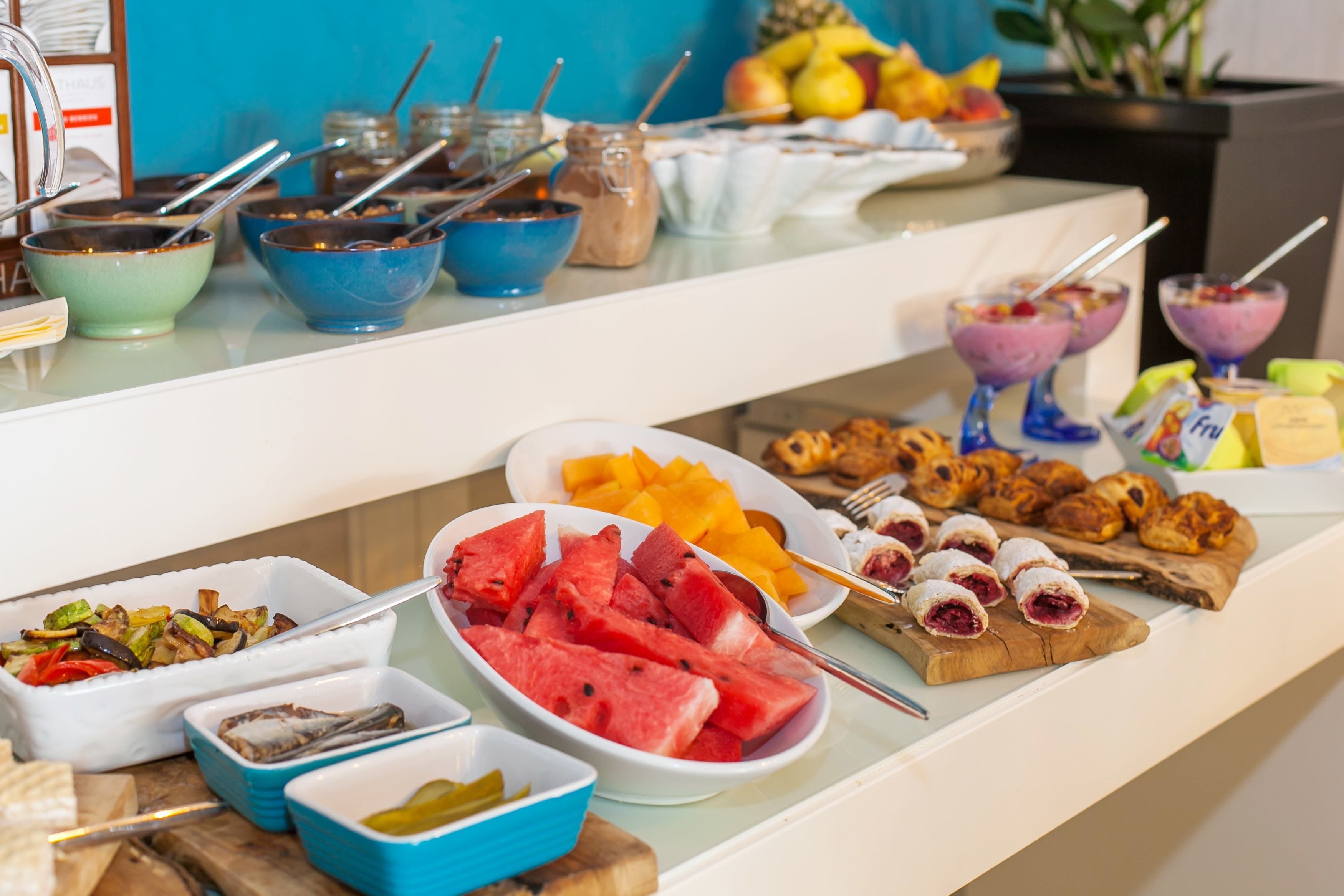 Ein Buffet mit verschiedenen Speisen, darunter Obst, Gebäck und ein Salat.