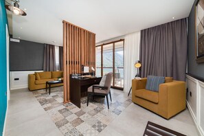 Un salon moderne avec un canapé, un bureau et une chaise. Il y a une grande fenêtre avec des rideaux, et une vue sur les montagnes.