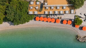 An aerial view of a coastal property with a wooden deck, outdoor seating, and a clear turquoise sea. - Hotel Casa del Mare - Amfora (Orahovac)