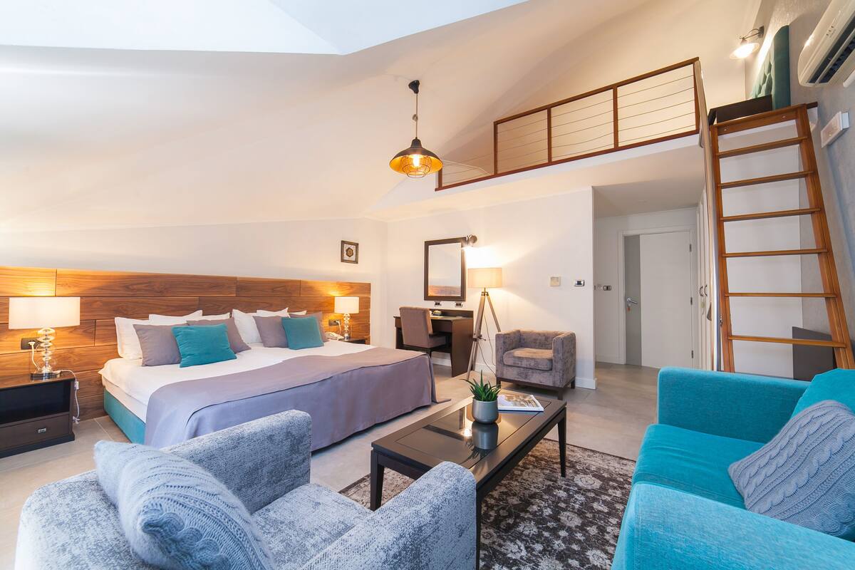 Een moderne hotelkamer met een hoogslaper, een bureau, een stoel, een bank en een trap.