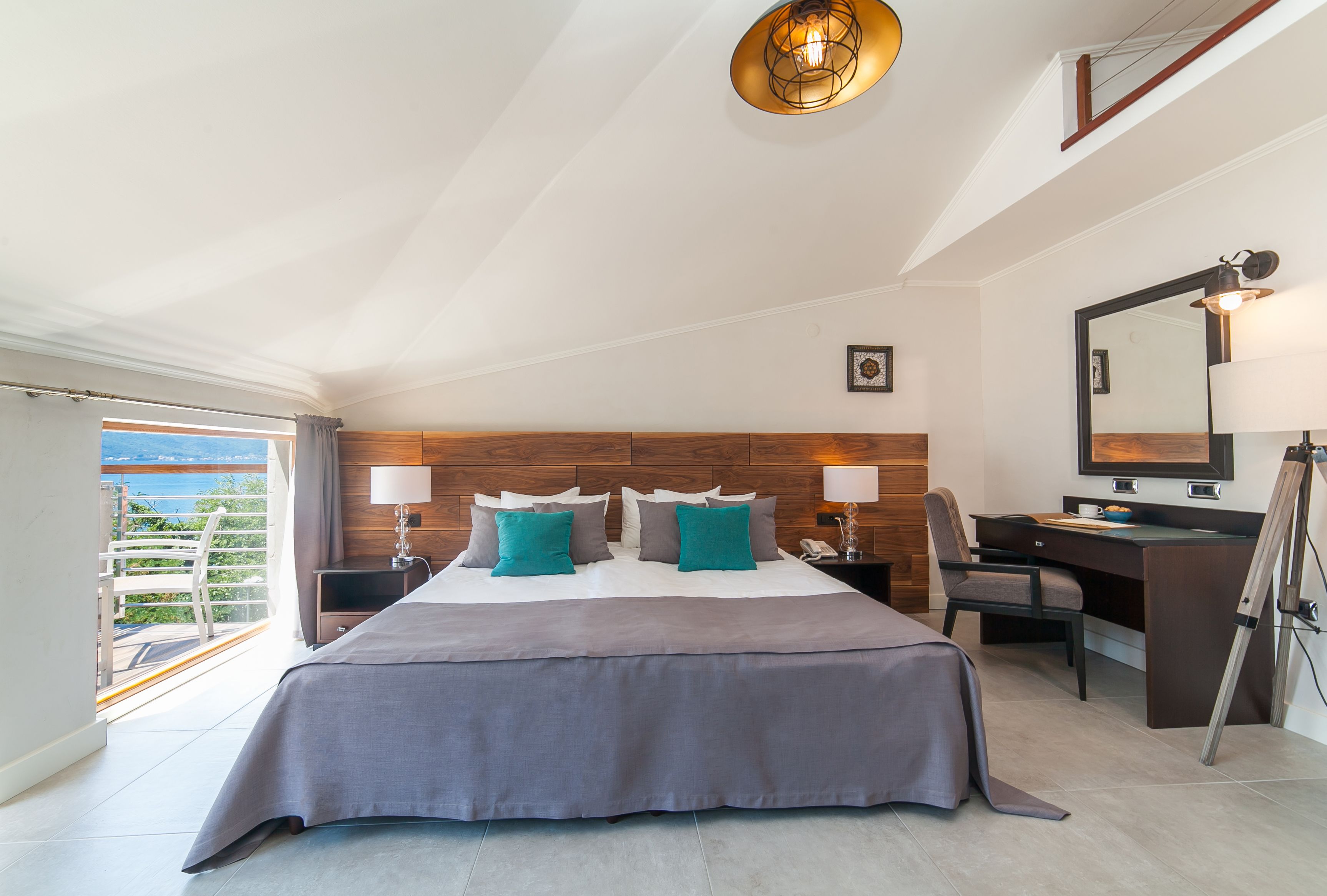 Une chambre d’hôtel moderne dotée d’un grand lit, d’un bureau et d’un balcon avec vue.