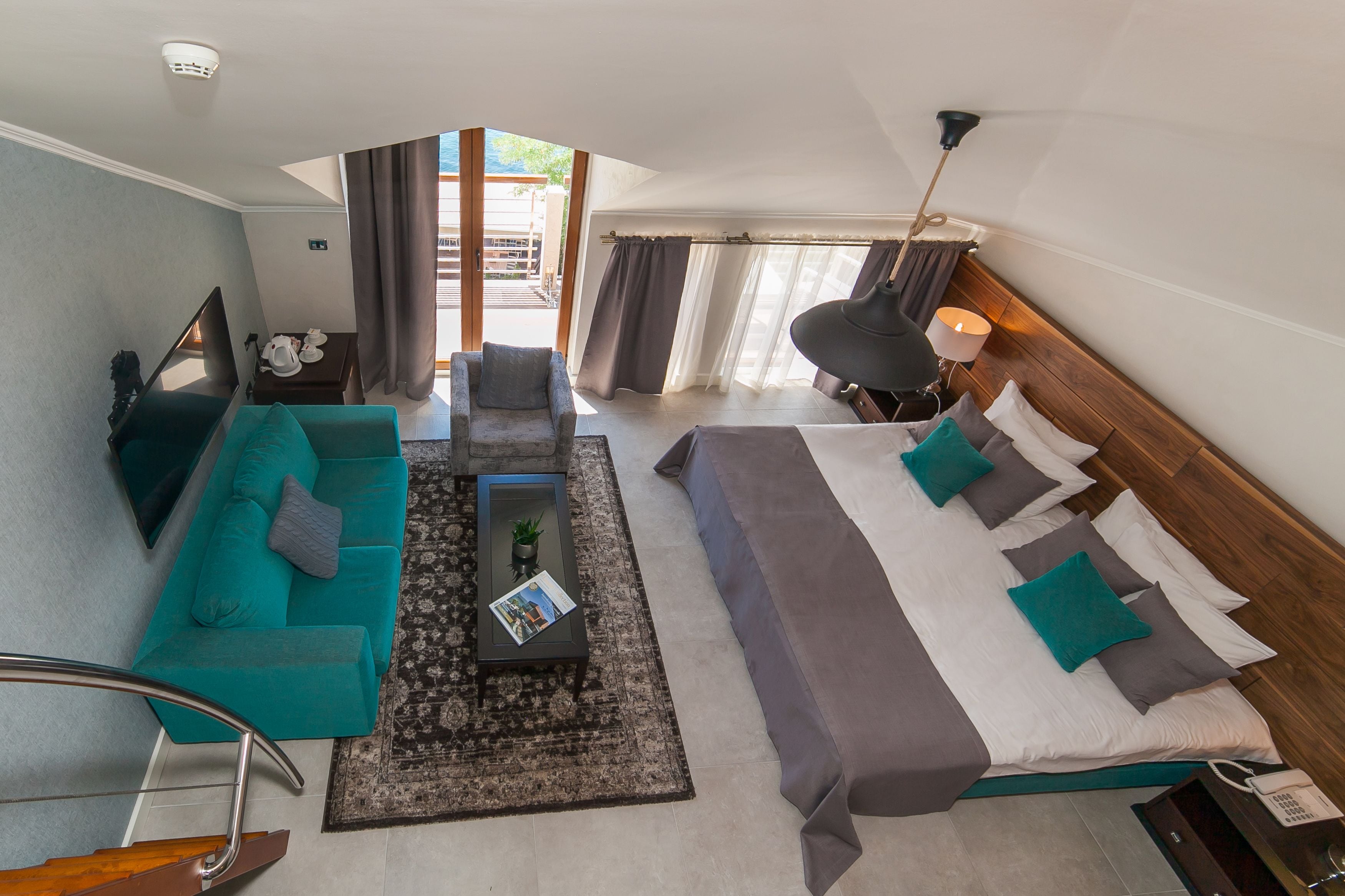 Una habitación de hotel moderna con sofá, cama, una mesita de centro y vistas al exterior.