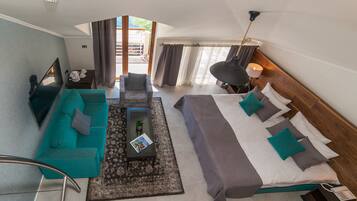 Una habitación de hotel moderna con sofá, cama, una mesita de centro y vistas al exterior.