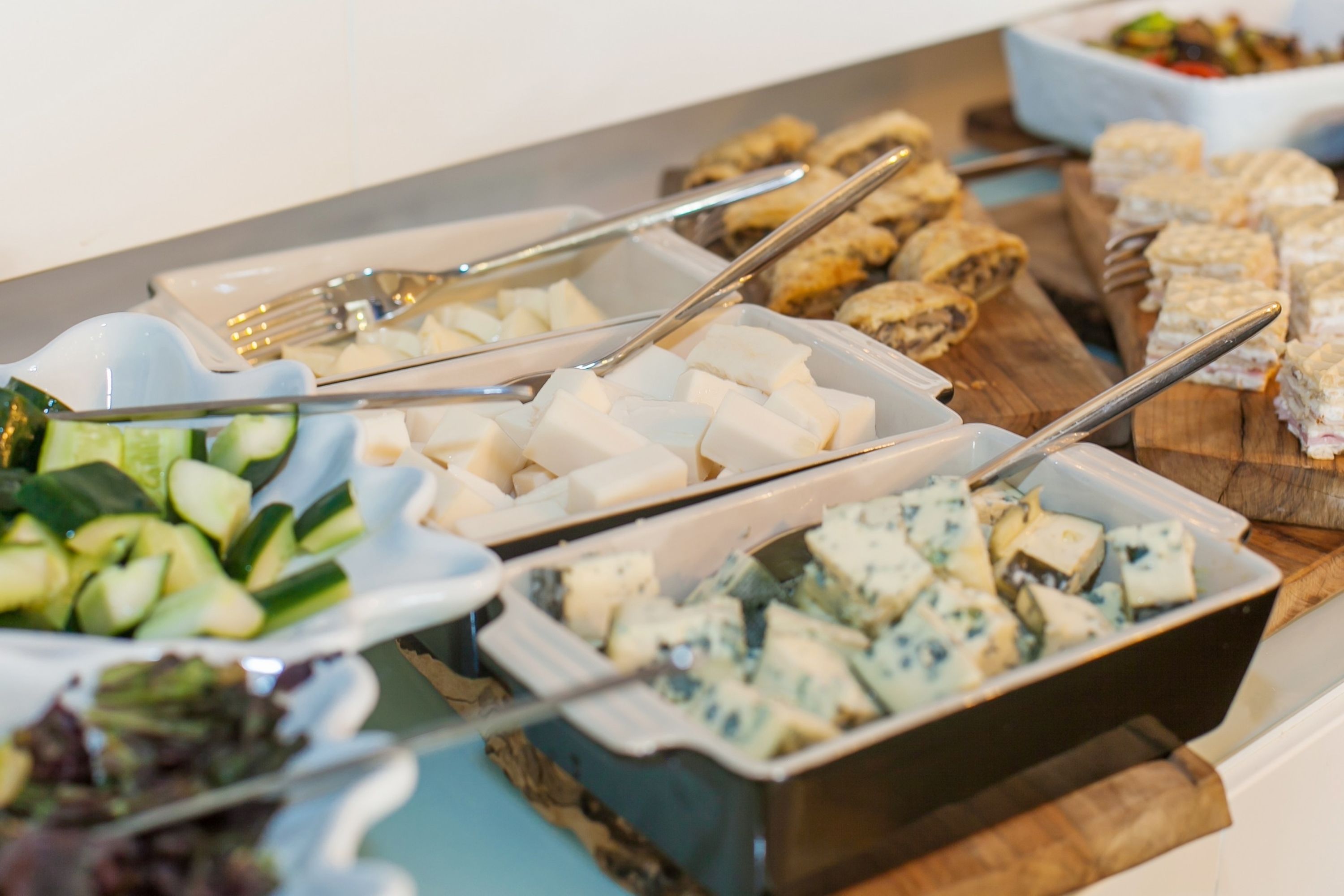A buffet with various food items including cheese, vegetables, and other dishes.