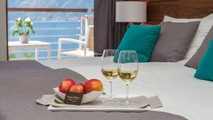 A hotel room with a bed, two wine glasses, a bowl of fruit, and a view of the sea. - Hotel Casa del Mare - Amfora (Orahovac)