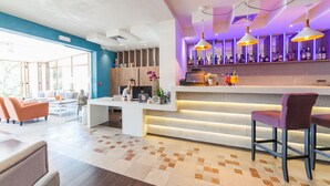 Un hall d’hôtel moderne comprenant un comptoir d’accueil, un espace salon et un bar.