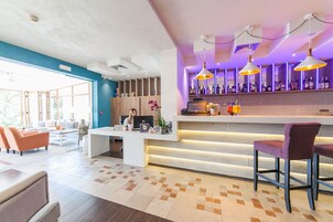 Un moderno vestíbulo de hotel con recepción, zona de estar y bar.
