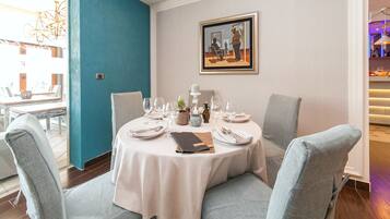 A dining area with a round table set for four, chairs, and a painting on the wall.
