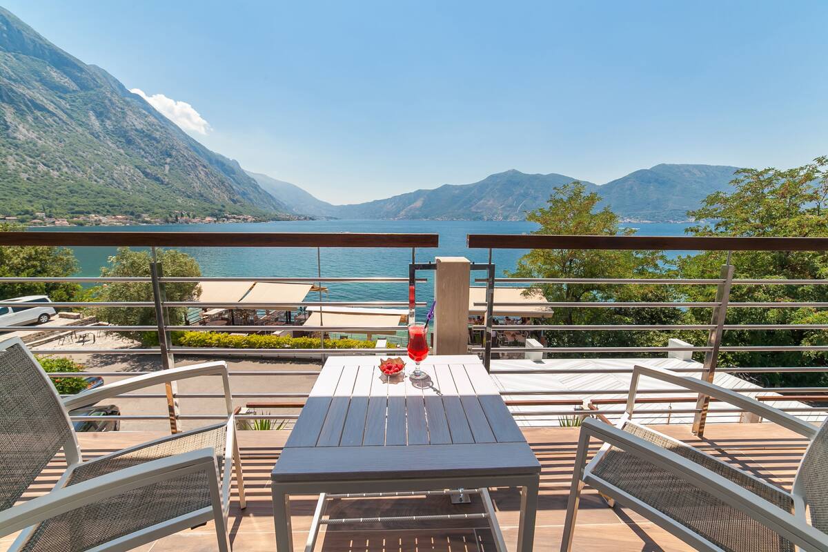 Een terras met een tafel en stoelen, met uitzicht op een meer en bergen.