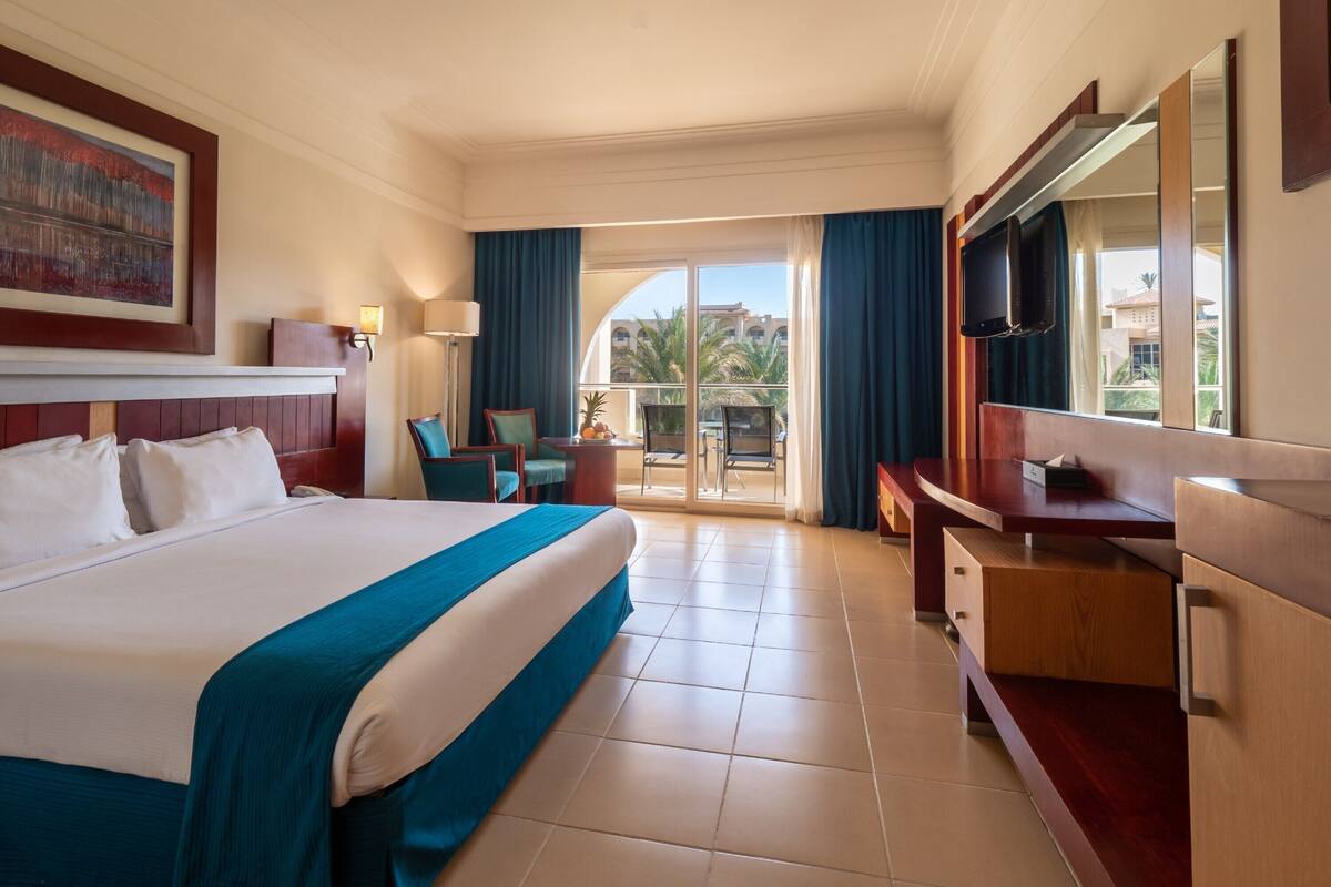 Une chambre d’hôtel avec un grand lit, un bureau, une télévision et un balcon avec vue.