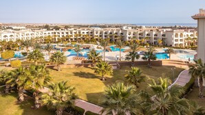 Ein Resort mit mehreren Pools, Palmen und Blick auf das Meer.
