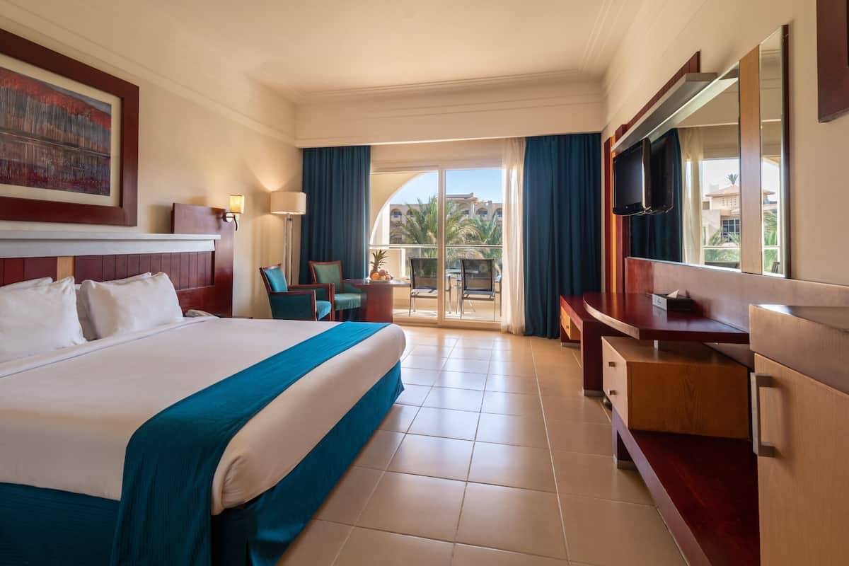 Une chambre d’hôtel avec un grand lit, un bureau, une télévision et un balcon avec vue.