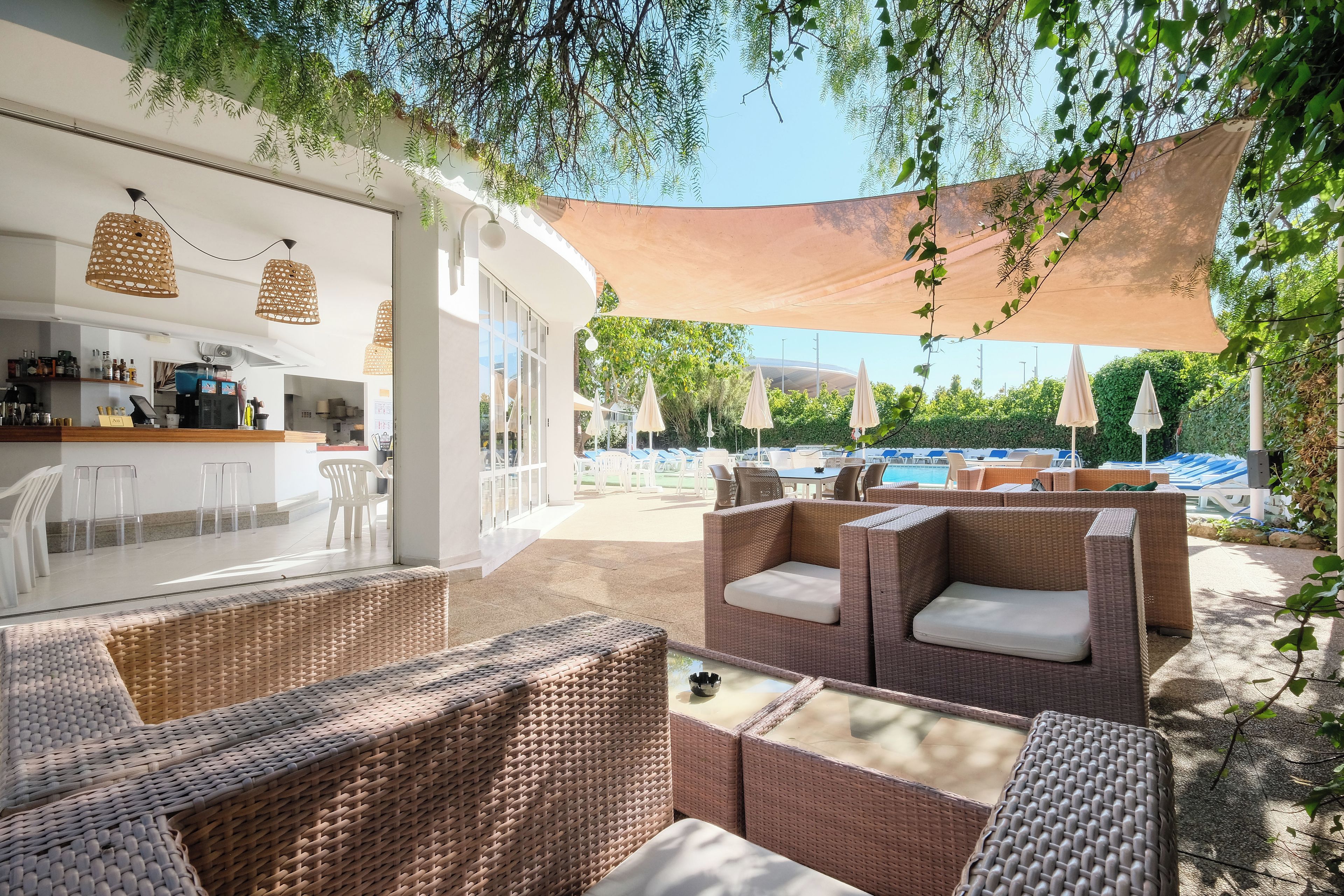 An outdoor seating area with wicker furniture and a pool in the background.