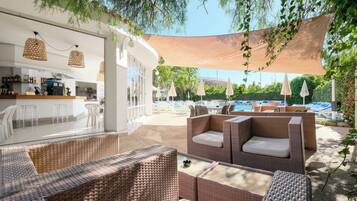 An outdoor seating area with wicker furniture and a pool in the background.