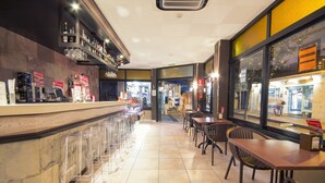 A modern bar area with a long counter, clear plastic stools, and a variety of bottles and glasses on shelves. - azuLine Hotel Llevant (Sant Antoni de Portmany)