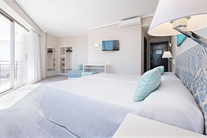 A modern hotel room with a large bed, a desk, a TV, and a balcony. - Azuline Hotel Llevant (Sant Antoni de Portmany)