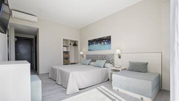 Une chambre d’hôtel avec deux lits, un bureau, une chaise, une télévision et un tableau au mur.