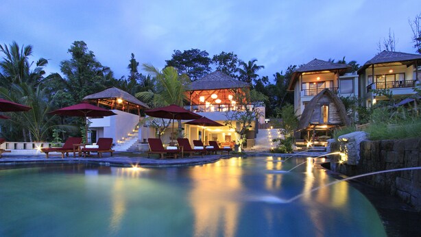 A resort with a swimming pool, lounge chairs, and thatched-roof structures. - Puri Sebali Resort (Ubud)