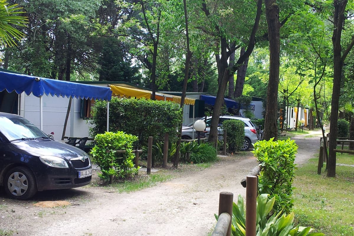 Un campamento con tiendas de campaña, un coche y un sendero.